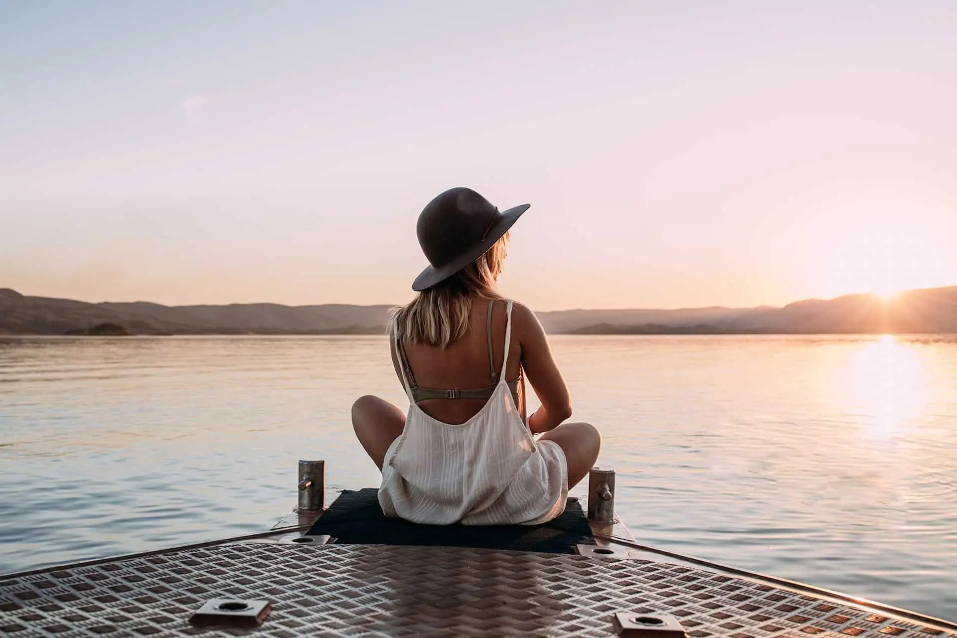 A woman meditating in front of the lake at sunrise